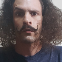 Close up of Derick's head. He has one eyebrow raised, a handle bar moustache (both ends point upwards, like a b-grade Salvador Dali), and wild, curly hair. It's supposed to elicit  the sense that Derick doesn't take himself too seriously.